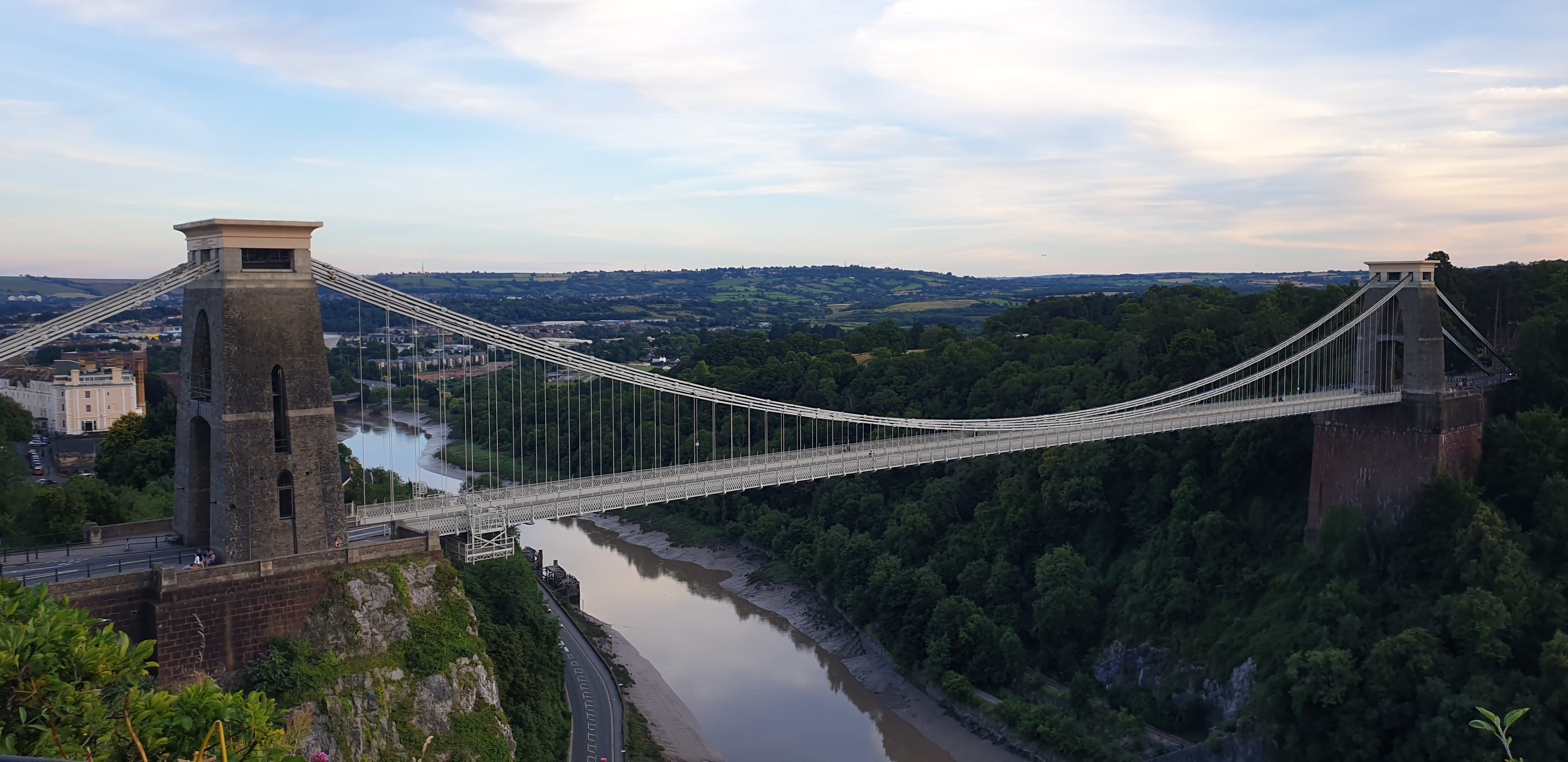 a photo of Clifton suspension bridge, taken from a nearbyhillside, with the river avon below it and a blue dusky skyin the background